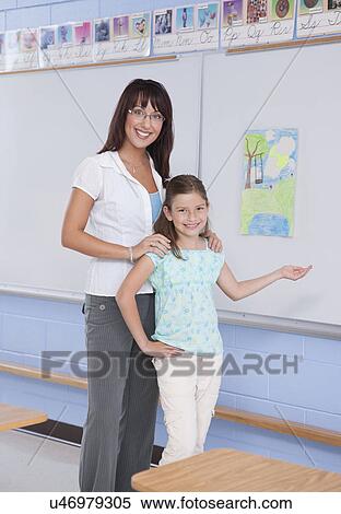Stock Photography - USA, Illinois, Metamora, Portrait of teacher with school girl (8-9) in classroom. Fotosearch