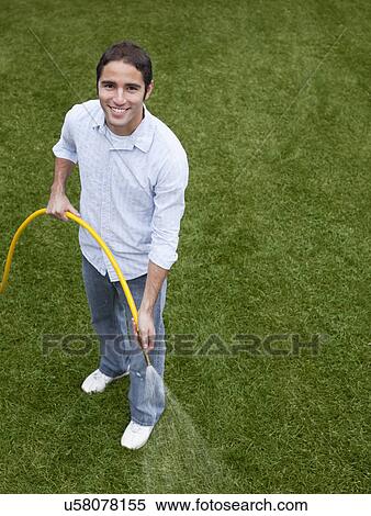 Stock Photography - USA, Illinois, Metamora, Portrait of young man with garden hose. Fotosearch