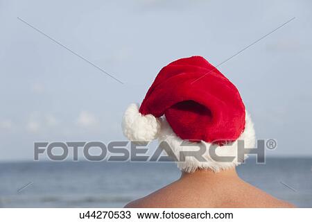 USA, Illinois, Metamora, Rear view of man wearing Santa hat facing lake View Large Photo Image Stock Image - USA, Illinois, Metamora, Rear view of man wearing Santa hat facing lake. Fotosearch