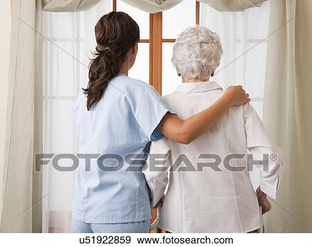 USA, Illinois, Metamora, Rear view of female nurse and senior woman looking through window View Large Photo Image Stock Photo - USA, Illinois, Metamora, Rear view of female nurse and senior woman looking through window. Fotosearch