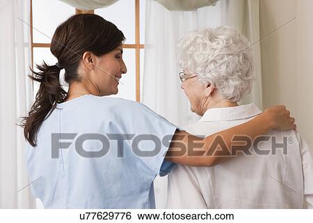 Stock Photograph - USA, Illinois, Metamora, Rear view of female nurse consoling senior woman. Fotosearch
