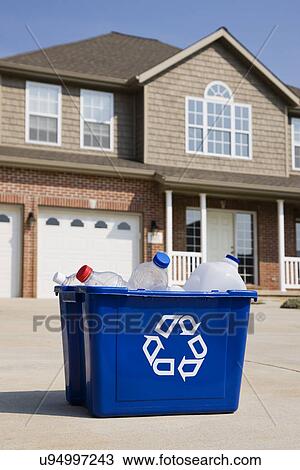 Stock Image - USA, Illinois, Metamora, Recycling bin in front of house. Fotosearch