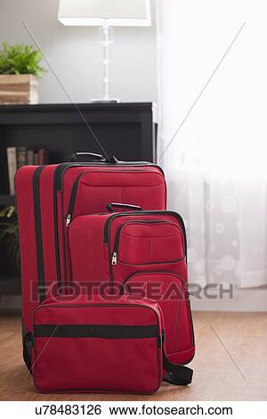 Stock Photograph - USA, Illinois, Metamora, Red suitcases in living room. Fotosearch