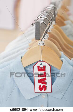 Picture - USA, Illinois, Metamora, Sale tag on clothing hanging on rail in shop. Fotosearch