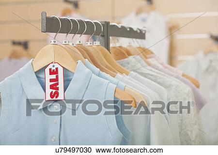 Stock Image - USA, Illinois, Metamora, Sale tag on clothing hanging on rail in shop. Fotosearch