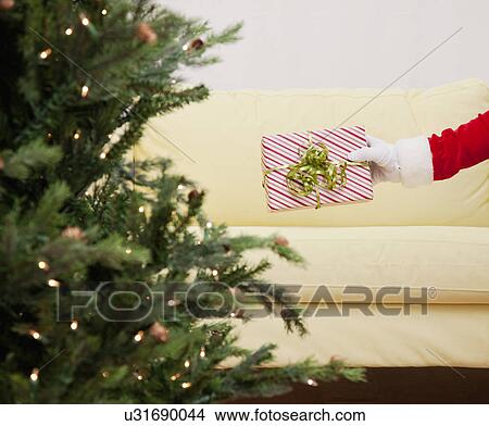 Picture - USA, Illinois, Metamora, Santa claus leaving present on sofa. Fotosearch