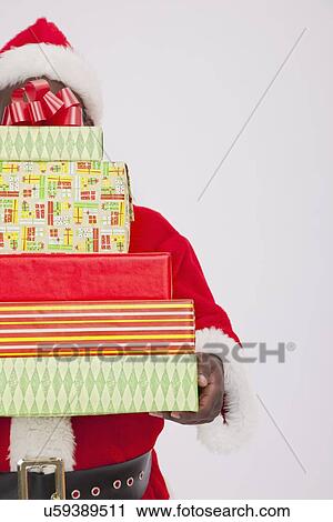 Stock Image - USA, Illinois, Metamora, Santa Claus holding stack of Christmas presents. Fotosearch