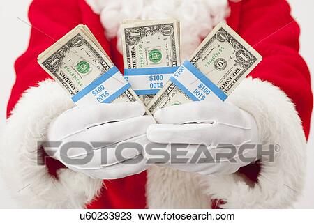 Stock Image - USA, Illinois, Metamora, Santa claus holding bundles of dollars. Fotosearch