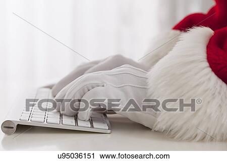 Stock Image - USA, Illinois, Metamora, Santa claus typing on keyboard. Fotosearch