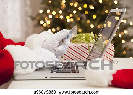 Stock Image - USA, Illinois, Metamora, Santa claus shopping with laptop and credit card. Fotosearch