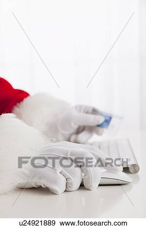 Stock Photo - USA, Illinois, Metamora, Santa claus shopping with computer and credit card. Fotosearch