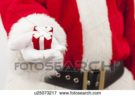 Stock Photo - USA, Illinois, Metamora, Santa claus holding small gift. Fotosearch
