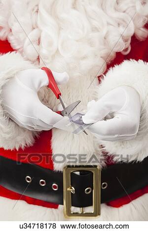 Stock Photo - USA, Illinois, Metamora, Santa claus cutting credit card. Fotosearch