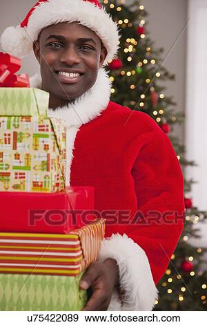 Stock Photo - USA, Illinois, Metamora, Santa Claus holding stack of Christmas presents. Fotosearch