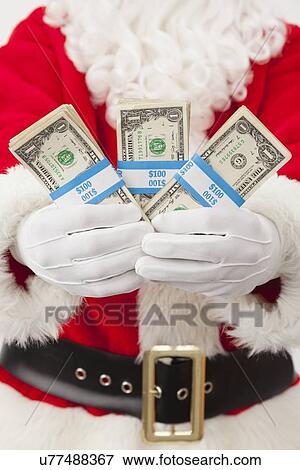 Stock Photo - USA, Illinois, Metamora, Santa claus holding bundles of dollars. Fotosearch