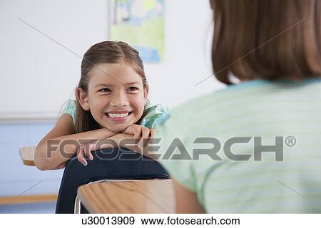 Stock Photo - USA, Illinois, Metamora, School girls (8-9) smiling in classroom. Fotosearch