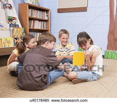 Stock Photography - USA, Illinois, Metamora, School children (8-9) reading on floor in school. Fotosearch