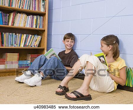 Stock Photography - USA, Illinois, Metamora, School children (8-9) reading on floor in school. Fotosearch