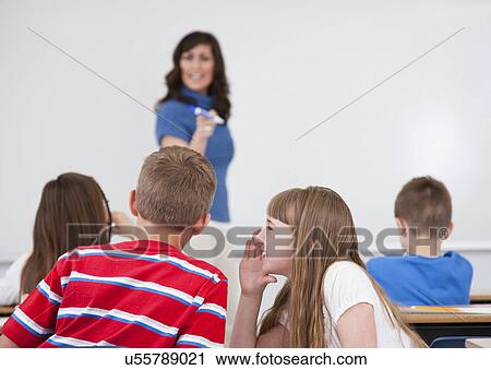 USA, Illinois, Metamora, Schoolchildren (8-9, 10-11) whispering in classroom, female teacher in background View Large Photo Image Stock Image - USA, Illinois, Metamora, Schoolchildren (8-9, 10-11) whispering in classroom, female teacher in background. Fotosearch