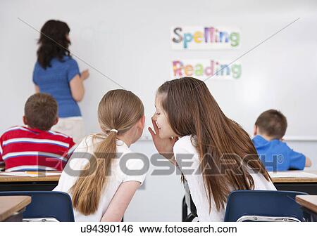USA, Illinois, Metamora, Schoolgirls (8-9, 10-11) whispering in classroom, female teacher at whiteboard in background View Large Photo Image Stock Photograph - USA, Illinois, Metamora, Schoolgirls (8-9, 10-11) whispering in classroom, female teacher at whiteboard in background. Fotosearch