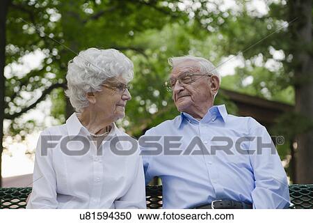 Stock Image - USA, Illinois, Metamora, Senior couple in sitting on bench park. Fotosearch