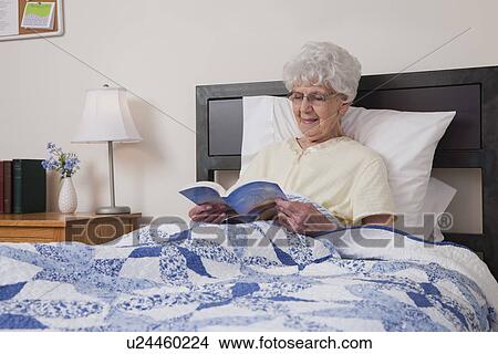 USA, Illinois, Metamora, Senior woman reading book in bed View Large Photo Image Picture - USA, Illinois, Metamora, Senior woman reading book in bed. Fotosearch