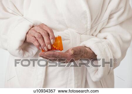 Stock Photo - USA, Illinois, Metamora, Senior woman pouring pills into hand. mid section. Fotosearch