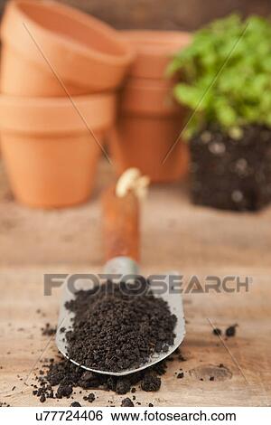 Stock Photograph - USA, Illinois, Metamora, Shovel with dirt, flower pots in background. Fotosearch