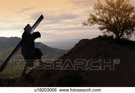 Stock Photograph - USA, Illinois, Metamora, Silhouette of man with cross climbing up hill. Fotosearch
