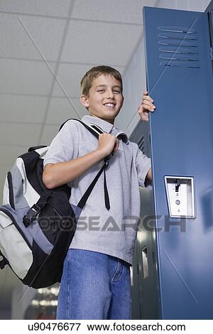 Stock Photo - USA, Illinois, Metamora, Smiling boy (10-11) standing at open locker in school corridor. Fotosearch