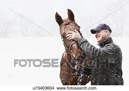 USA, Illinois, Metamora, Smiling mature man with horse during blizzard View Large Photo Image Picture - USA, Illinois, Metamora, Smiling mature man with horse during blizzard. Fotosearch