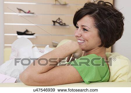 USA, Illinois, Metamora, Smiling young woman with shopping bags sitting on sofa in shoes store View Large Photo Image Stock Photo - USA, Illinois, Metamora, Smiling young woman with shopping bags sitting on sofa in shoes store. Fotosearch