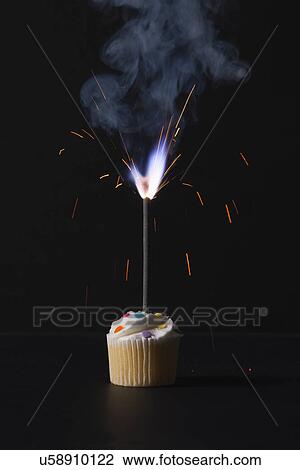 Stock Image - USA, Illinois, Metamora, Sparkler on cupcake. Fotosearch