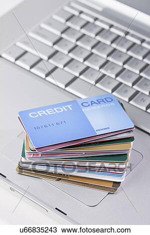 Stock Image - USA, Illinois, Metamora, Stack of credit cards on laptop computer. Fotosearch