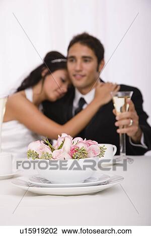 Stock Image - USA, Illinois, Metamora, Studio shot of bride and groom with flowers in foreground. Fotosearch