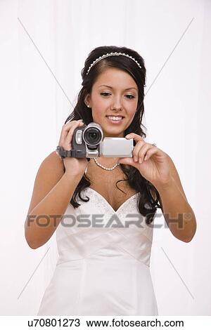 Stock Image - USA, Illinois, Metamora, Studio shot of bride using camcorder. Fotosearch