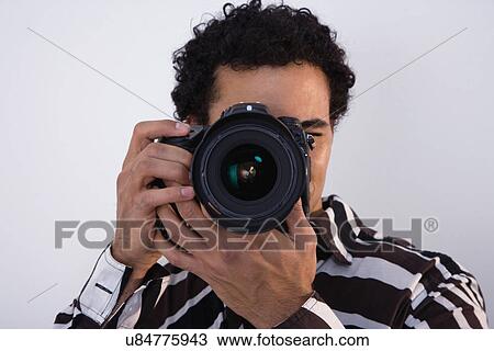 Stock Image - USA, Illinois, Metamora, studio shot of man taking photo with camera. Fotosearch