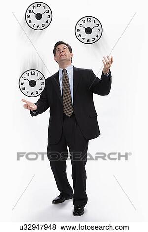 Stock Photo - USA, Illinois, Metamora, Studio shot of businessman juggling with clocks. Fotosearch