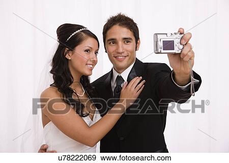 USA, Illinois, Metamora, Studio shot of bride and groom taking self Portrait photo View Large Photo Image Stock Photo - USA, Illinois, Metamora, Studio shot of bride and groom taking self Portrait photo. Fotosearch
