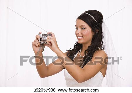 Stock Photo - USA, Illinois, Metamora, Studio shot of bride using digital camera. Fotosearch