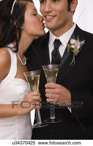 Stock Photography - USA, Illinois, Metamora, Studio shot of bride and groom toasting with champagne. Fotosearch