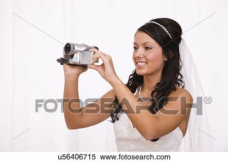 Stock Photography - USA, Illinois, Metamora, Studio shot of bride using camcorder. Fotosearch