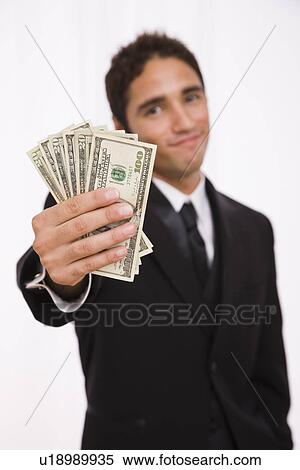 Stock Photography - USA, Illinois, Metamora, Studio shot businessman holding fanned out banknotes. Fotosearch