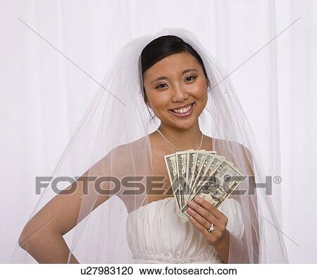 Stock Image - USA, Illinois, Metamora, Studio portrait of bride holding banknotes. Fotosearch