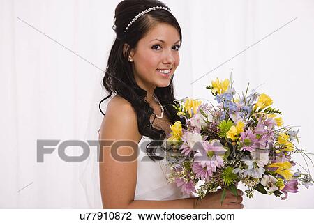 Stock Image - USA, Illinois, Metamora, Studio portrait of bride holding bouquet. Fotosearch