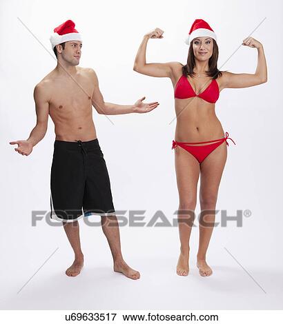 Stock Photo - USA, Illinois, Metamora, Studio portrait of couple in swimwear and Santa hats. Fotosearch