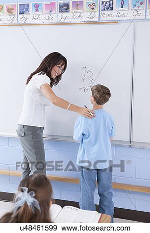 Stock Photo - USA, Illinois, Metamora, Teacher and students (8-9) in classroom. Fotosearch