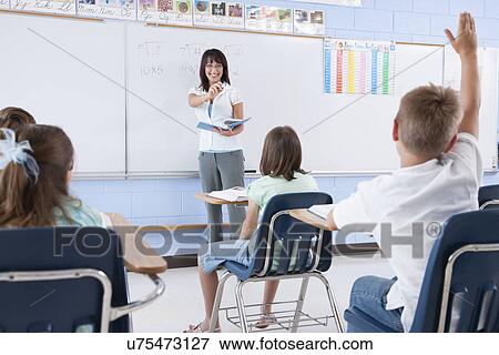 Stock Photo - USA, Illinois, Metamora, Teacher and students (8-9) in classroom. Fotosearch
