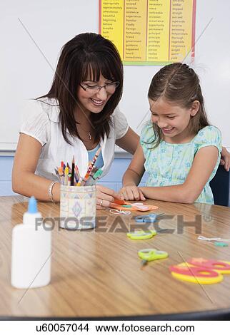 Picture - USA, Illinois, Metamora, Teacher assisting school girl (8-9) in classroom. Fotosearch