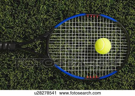Stock Image - USA, Illinois, Metamora, Tennis ball and tennis racket on grass. Fotosearch